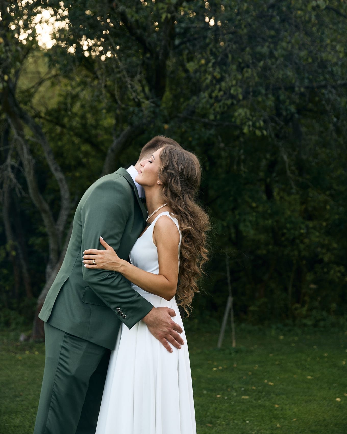 Long wavy hair falls down the bride's back as she leans into the groom's embrace, eyes closed