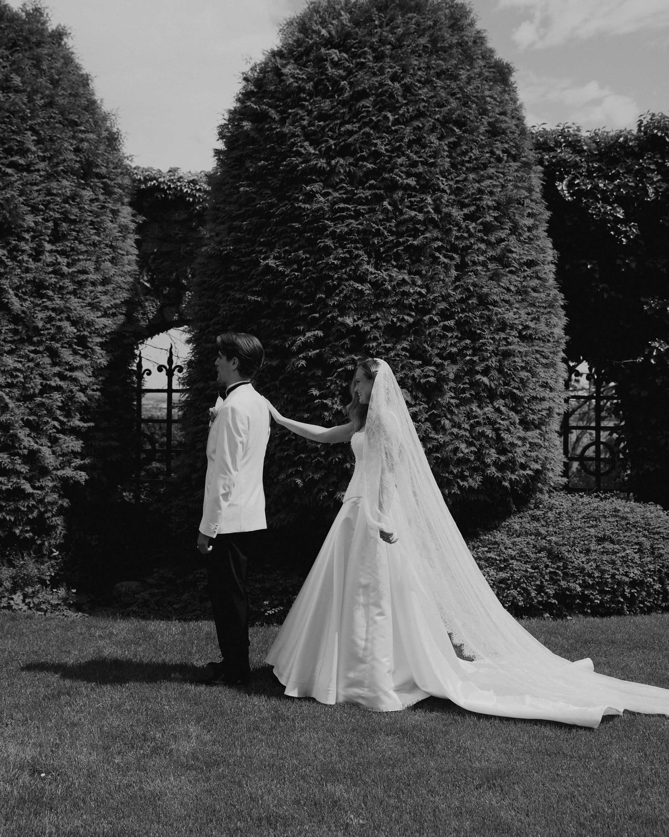 The groom reaching for the bride, her long train laid out behind
