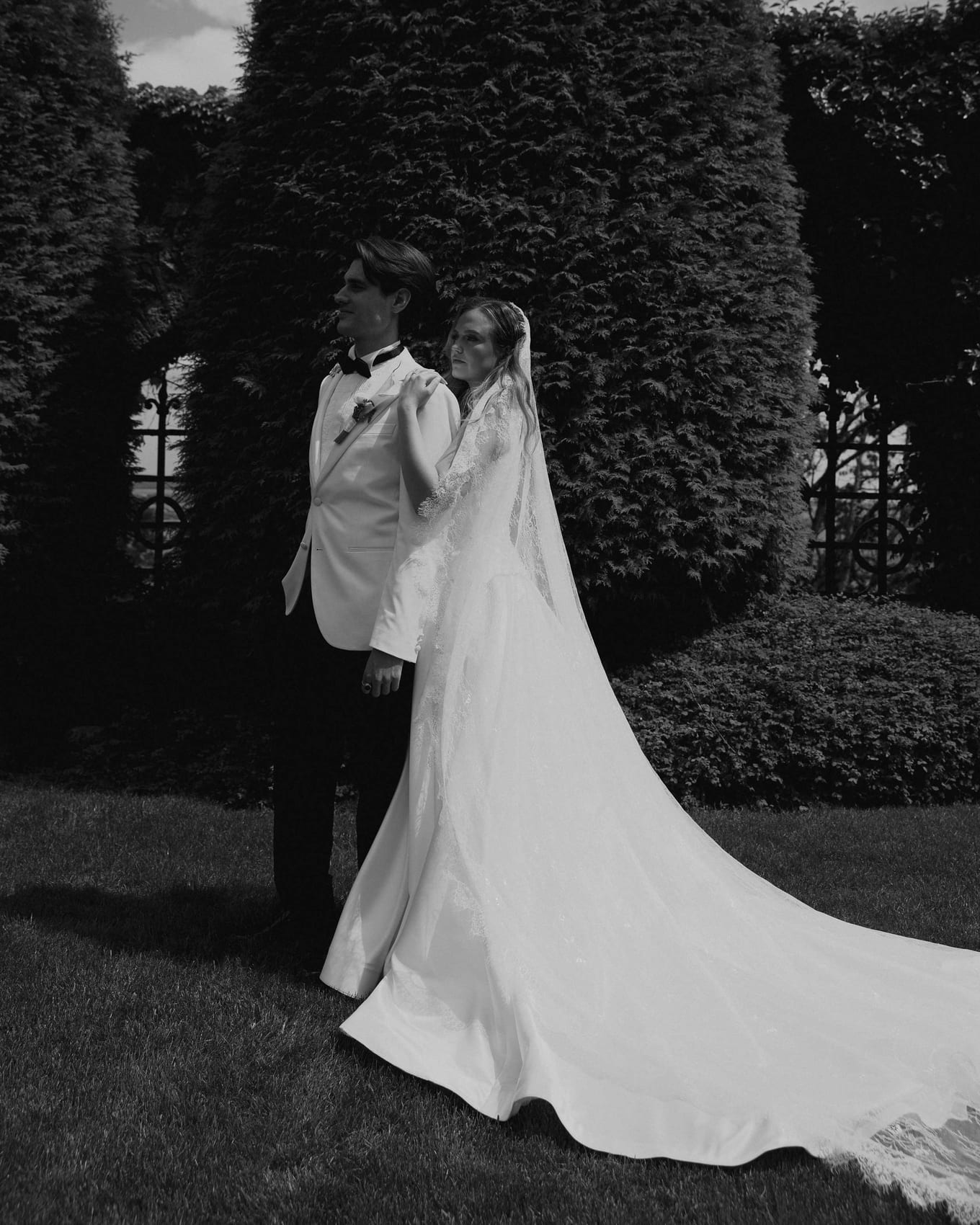 The couple holding one another in the formal garden