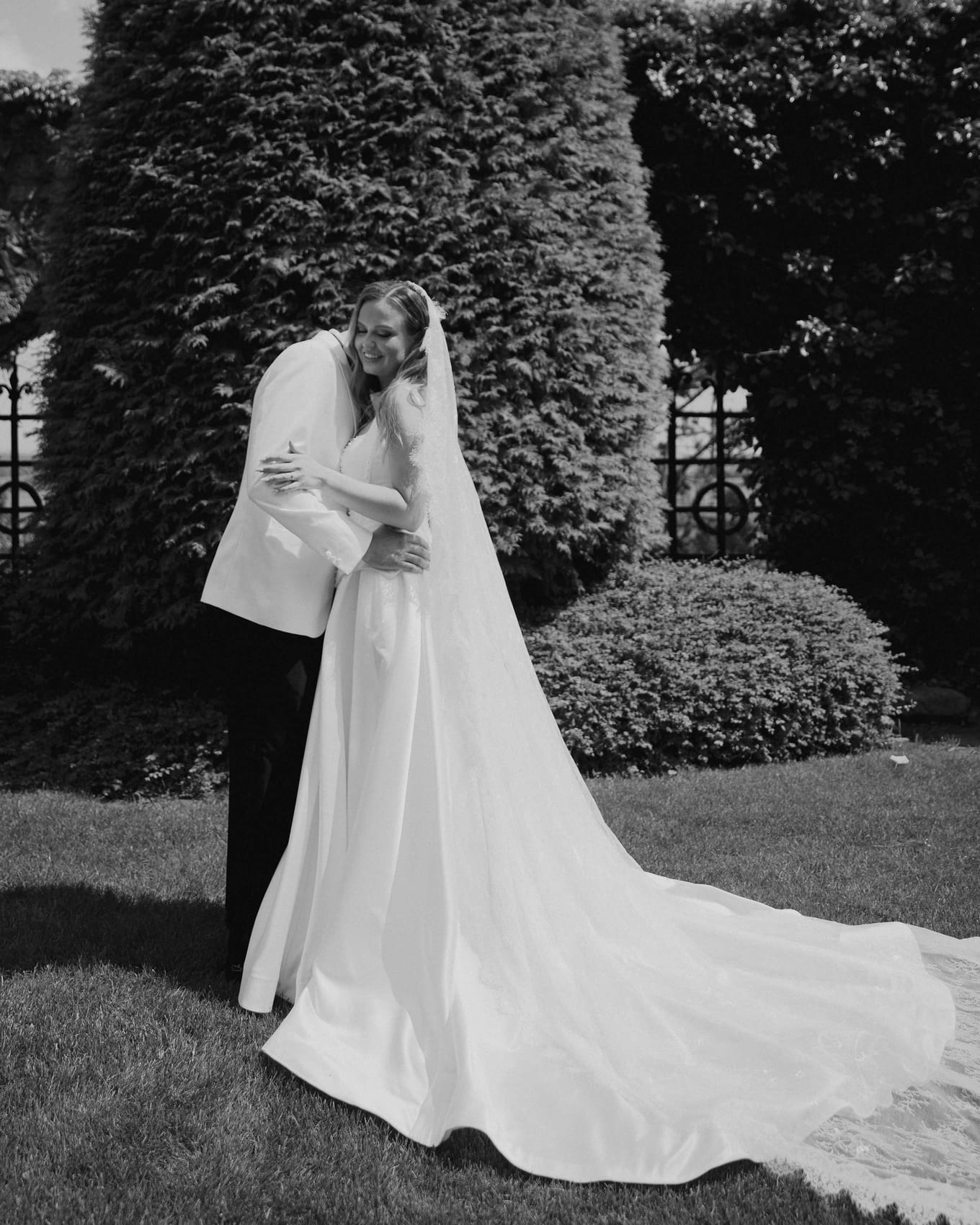 The couple embracing, the cathedral-length veil across the lawn