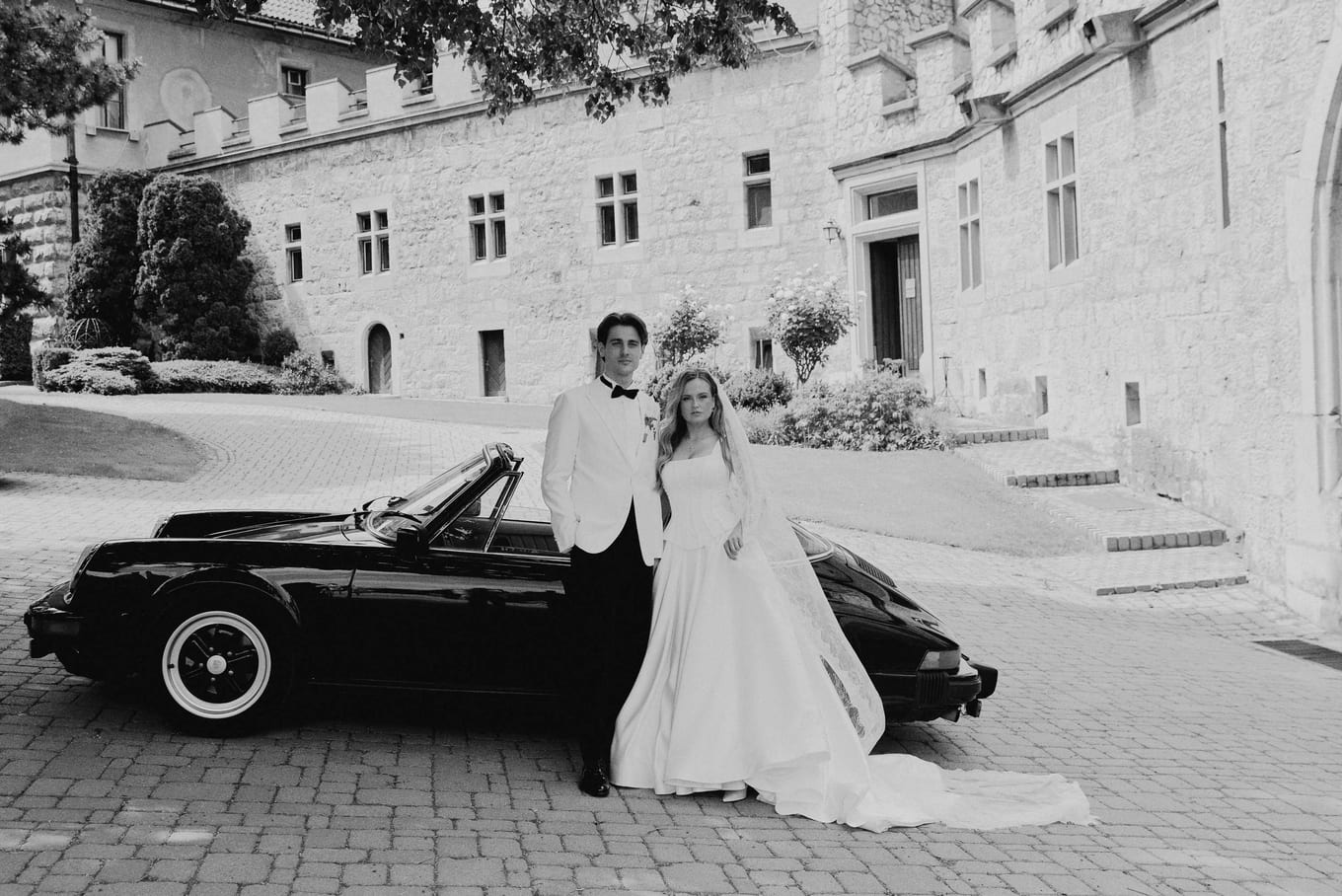 The couple leaning against the car in front of the château