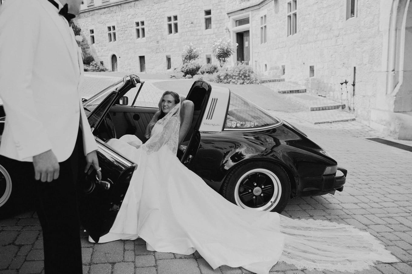 The groom holding the car door as the bride settles in