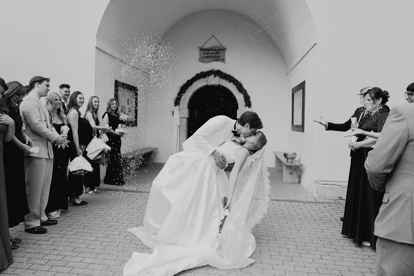 A kiss in the church doorway as guests throw confetti