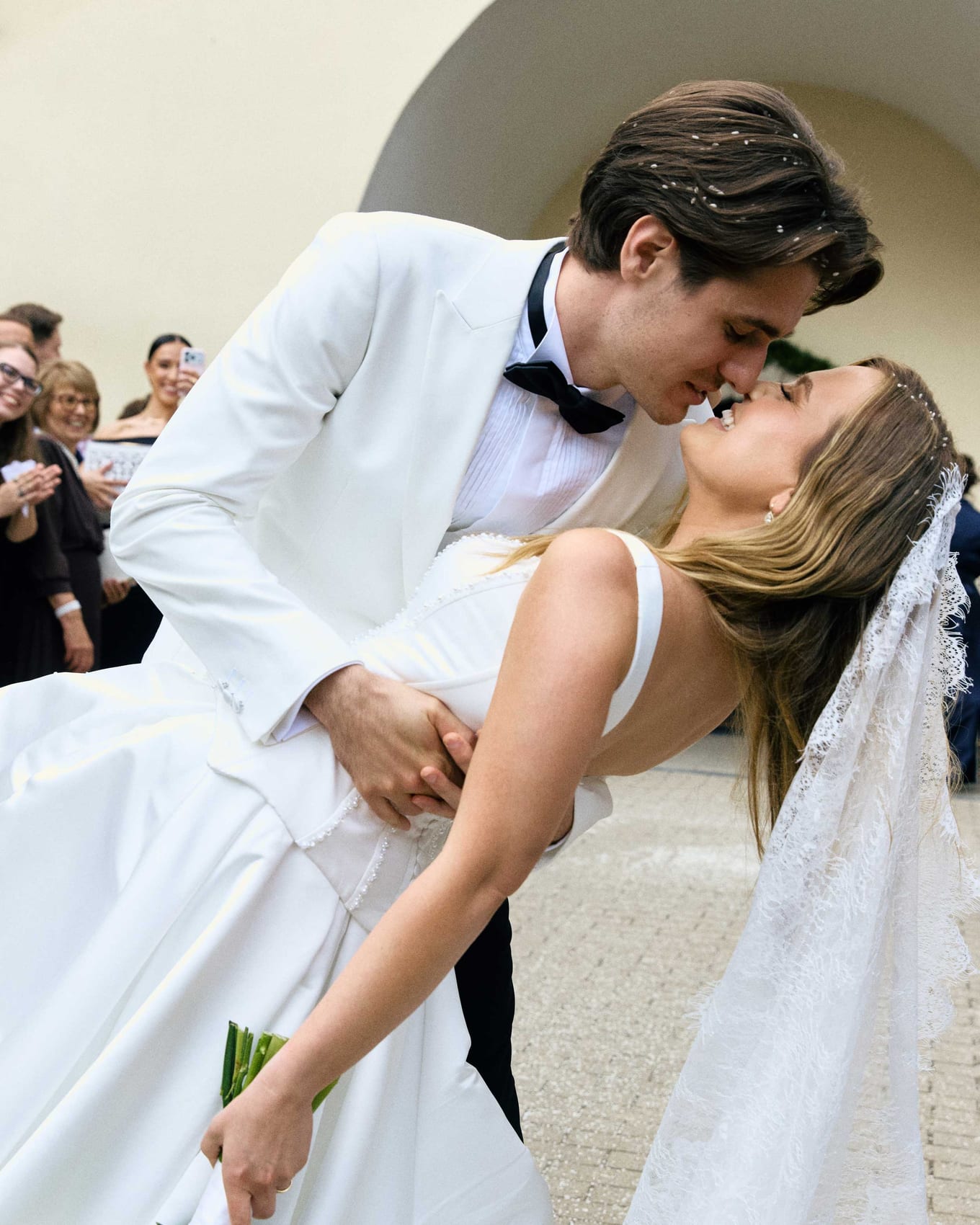 A kiss outside the church surrounded by guests
