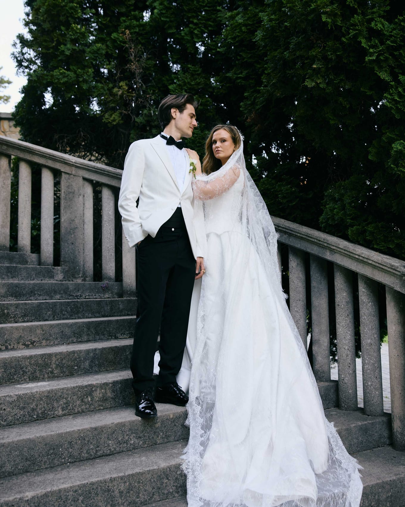 Bride and groom on the steps, veil trailing behind