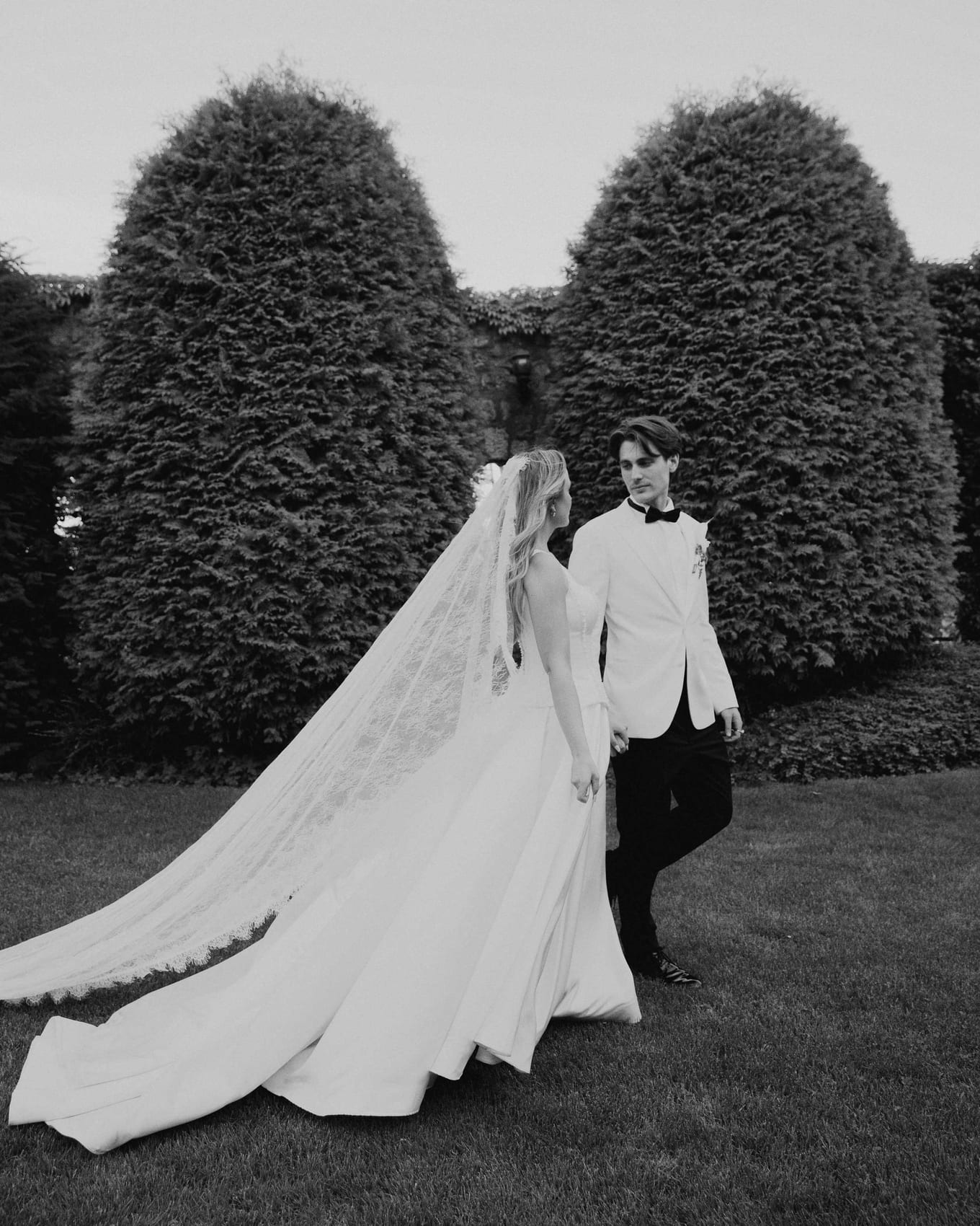 The veil and train sweeping the grass as they walk