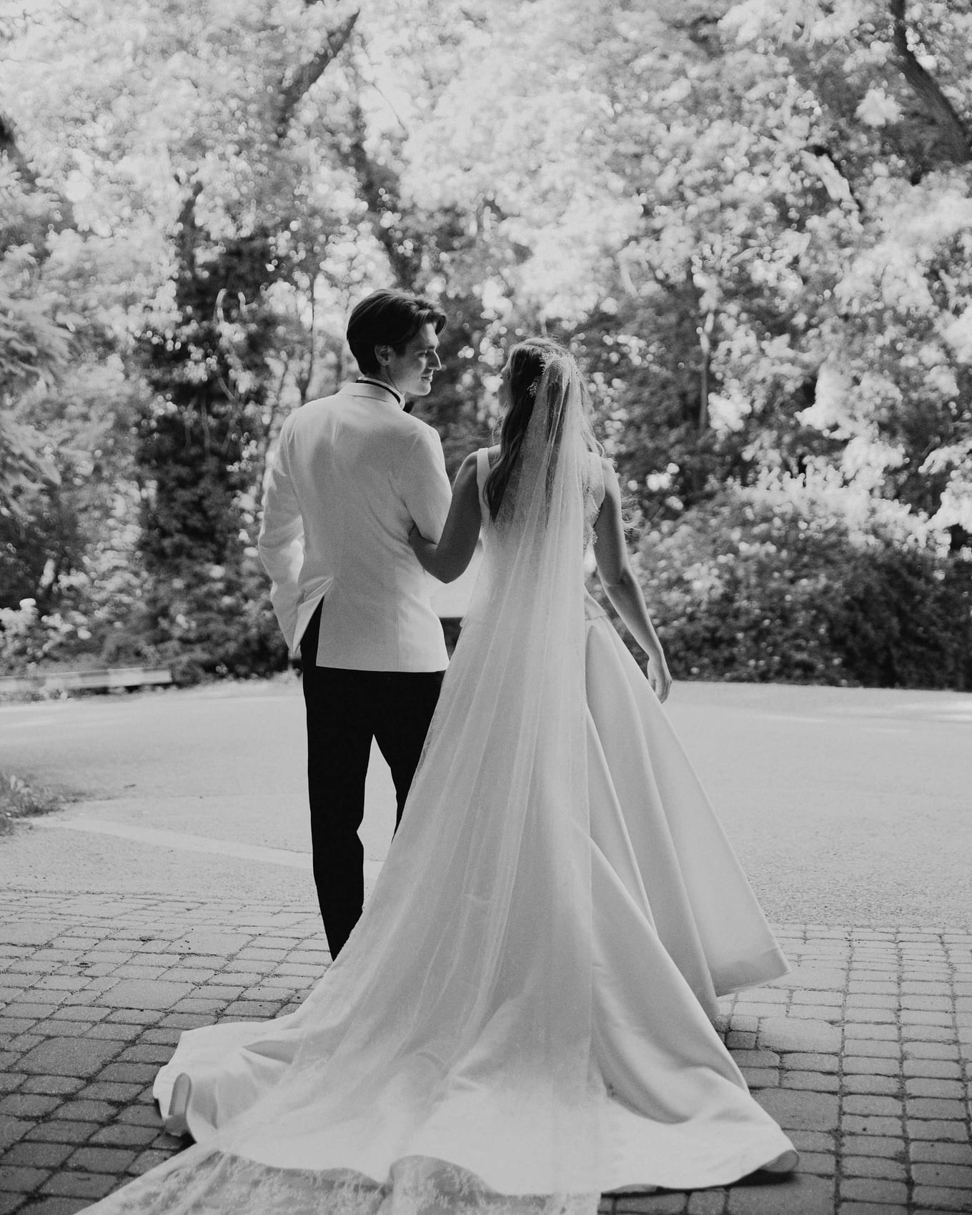 The groom lifting the bride's veil on the path