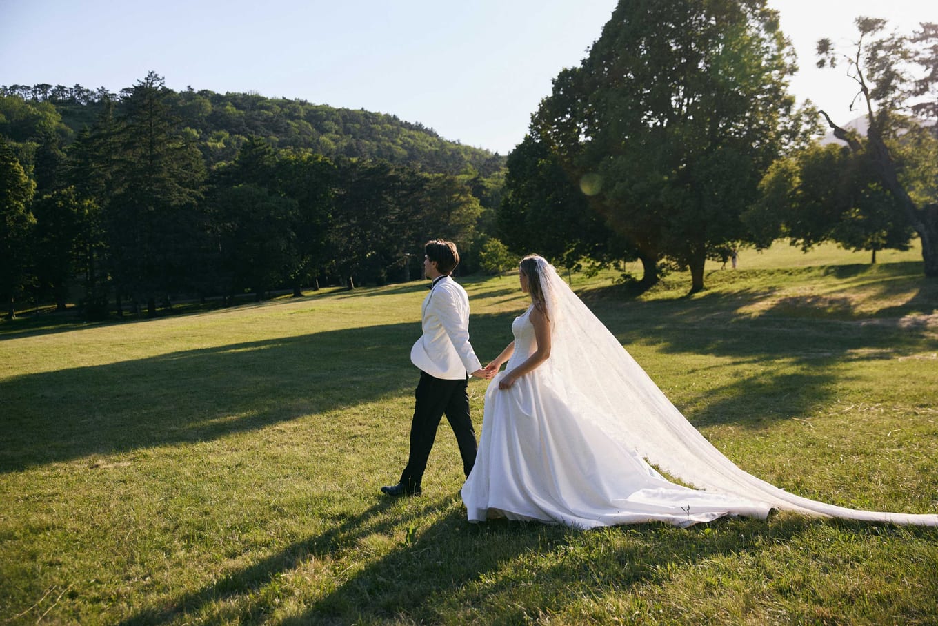 The couple walking hand in hand across the field